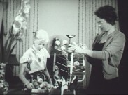 Mor och dotter julpyntar med äpplen och levande ljus.