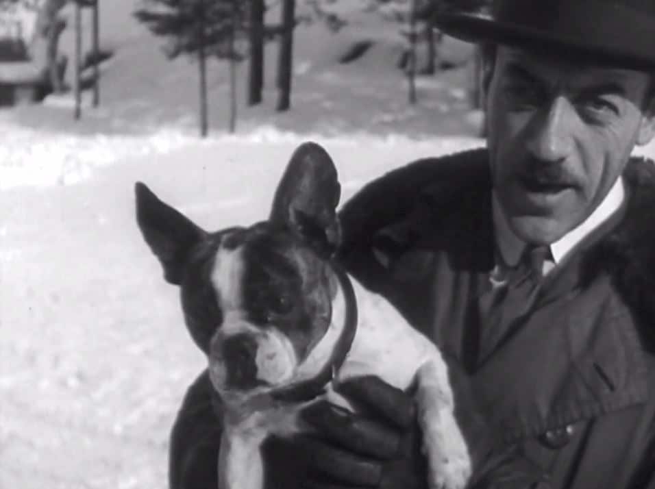 Mauritz Stiller håller i en hund, snö i bakgrunden.