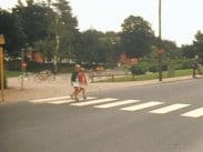 Två barn korsar ett övergångsställe, cykelparkering i bakgrunden.