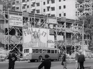 Halvfärdigt hus i Stockholm med en reklamaffisch för premiärfilmen "Full i sjutton" med Deanna Durbin, buss och människor i förgrunden.