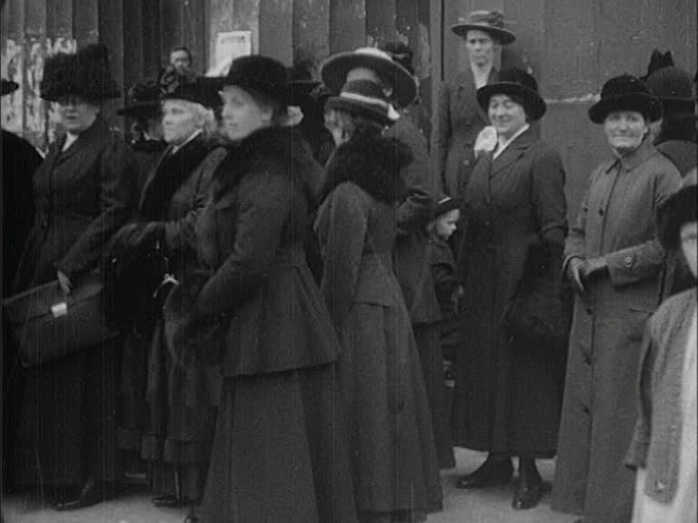 En samling kvinnor på trottoaren framför kanslihuset i Stockholm i samband med en kvinnorösträttdeputation hos statsministern 1917.