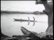 Tre män i roddbåt i Kongo, två av männen ror stående och den tredje sitter ner.