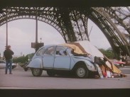 En gammal ljusblå Citroën 2CV har kört in i ett stånd med kläder.