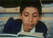 En skolpojke läser i en bok.