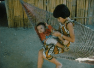 En liten flicka i en hängmatta tilsammans med ett spädbarn.
