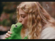En stillbild tagen ur filmen Ers Majestät (1981). En ung kvinna kysser en groda i tyg.