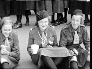 Tre unga kvinnliga scouter i full mundering.