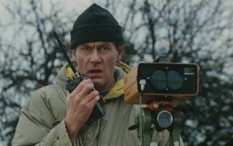 En man med mätutrustning på stativ talar i en walkie talkie.