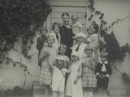 Svartvitt foto av ett tiotal barn och ett par vuxna samlade på en låg trappa framför en byggnad beväxt av murgröna.