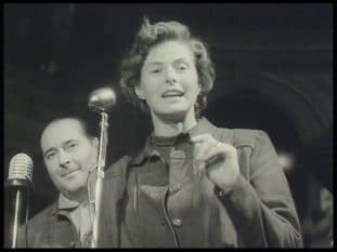 Ingrid Bergman vid mikrofon och Roberto Rossellini i bakgrunden.