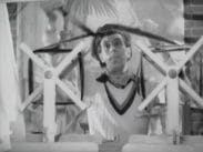 Martin Ljung i v-ringad tröja mellan två hemmabyggda filmprojektorer i trä på vilka han har laddat en filmremsa.