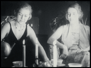 Två kvinnor bakom tända stearinljus.