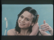 Mörkhårig kvinna kammar håret i reklamfilm för schampo.