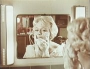 Christina Schollin tvålar in sitt ansikte framför en spegel.