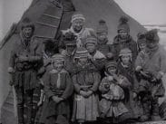 Ett tiotal samiska ungdomar uppställda för fotografering framför en kåta.