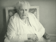 En äldre sittandes kvinna klädd i vitt.