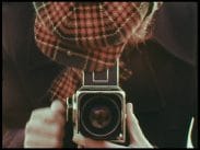En fotograf med rutig keps böjd över en Hasselblads-kamera.