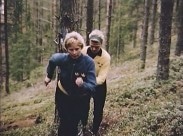 Två kvinnliga joggare i svensk landslagsdress på träningsrunda i skogen.
