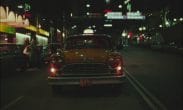 En stillbild tagen ur filmen Nattpass (1982). Gul taxibil i storstad på natten fotad framirfrån.