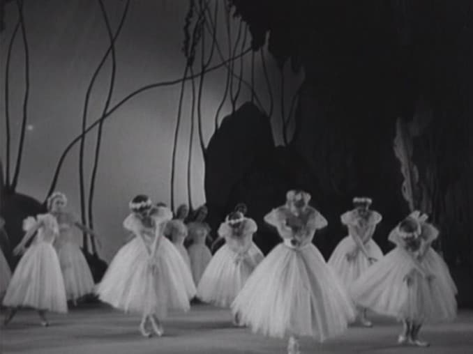 Ett tiotal balletdansöser i vita klänningar på scen, kuliss i bakgrunden.