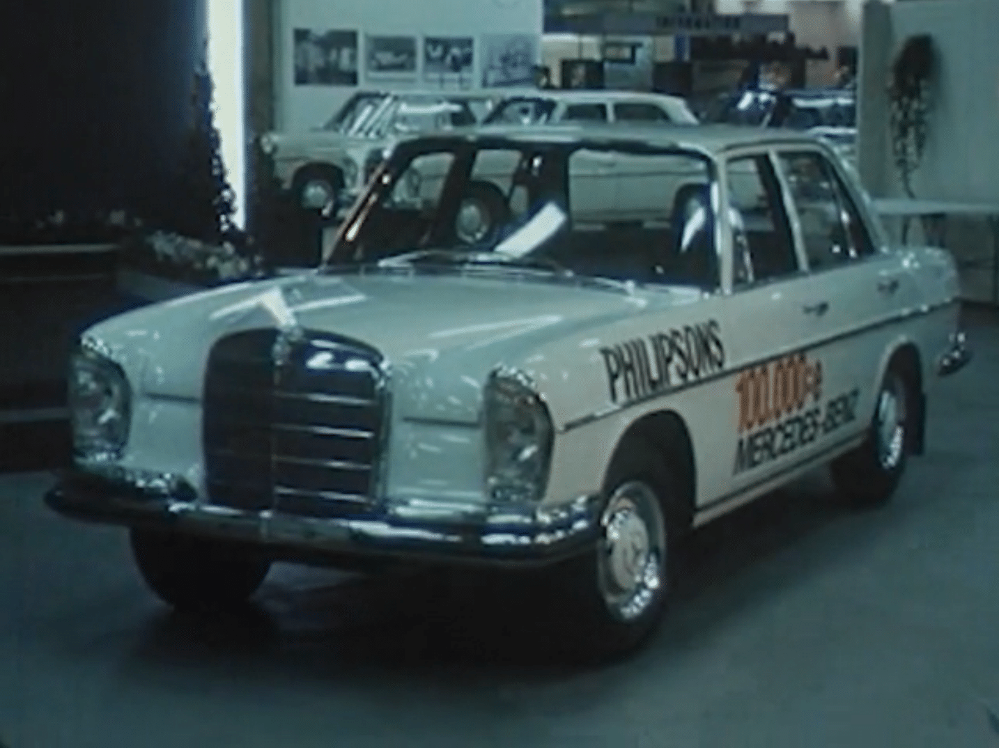 Vit Mercedes 250S personbil med texten Philipsons 100.000:e Mercedes-Benz på karossen.