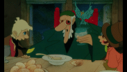En äldre trollkarl till bords omgiven av två barn (animerat).