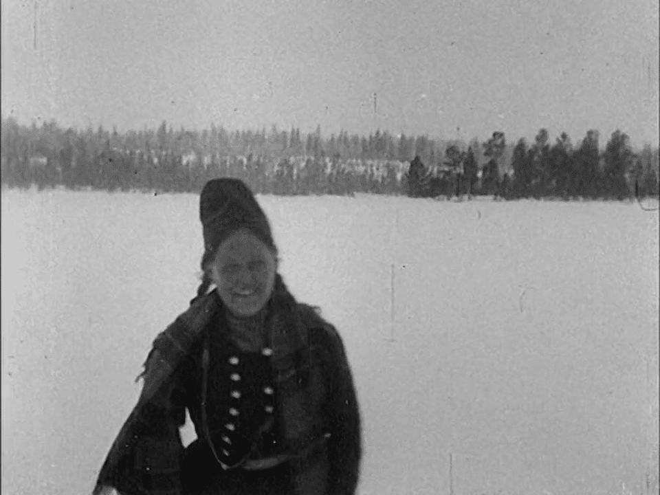 Samisk kvinna i vinterlandskap.