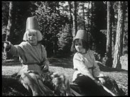 De båda trollpojkarna, Sotlugg och Linlugg, sitter på en klipphäll i skogen.