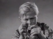 En pojke trär en tråd genom ett nålsöga.