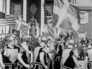 Kvinnor i vikingakläder tågar runt med amerikanska flaggor, i mitten även en svensk fana.