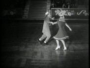 En man och en kvinna dansar jitterbug på ett dansgolv.