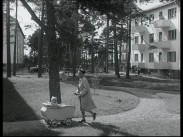 En kvinna drar en barnvagn i ett bostadsområde med nybyggda flerfamiljshus i slutet av 1940-talet.