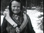 En liten samisk flicka, snö i bakgrunden.