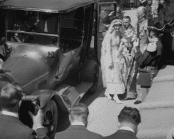 Prinsessan Margaretha av Danmark på väg till sitt bröllop med prins Axel av Danmark. Hon och prins Carl har precis stigit ur en bil. Pressfotografer dokumenterar händelsen.