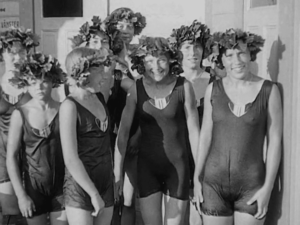 Simpromotion i Strömbadet, åtta simmerskor med kransar på huvudet.