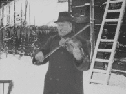 Bild på Skansens spelman Gustaf Ekström som spelar fjol utomhus.