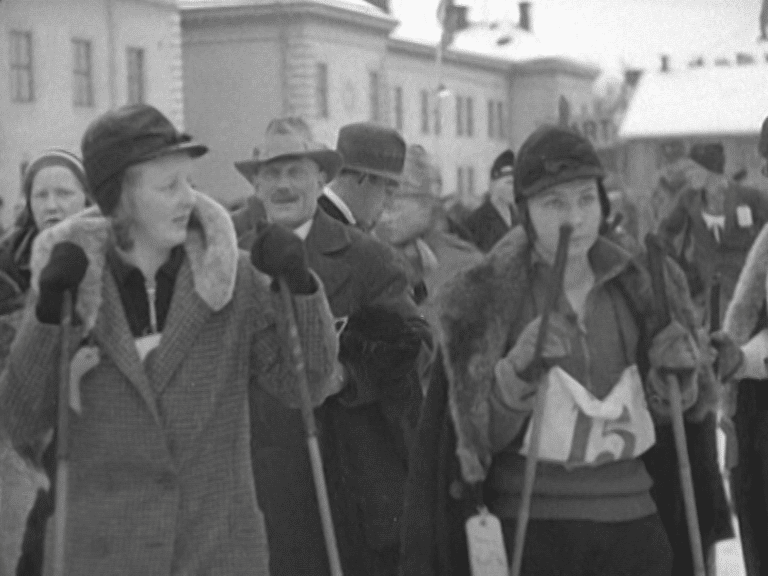Ett par kvinnliga skidlöpare inför start på SM i Östersund 1932, publik i bakgrunden.