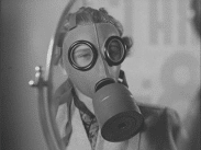 Kvinna iklädd gasmask ser sig själv i spegel.