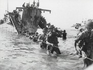 Militärer från ett krigsfartyg vadar iland på rad längst ett sträckt rep, bild från de allierades trupper vid landstigningen på Sicilien 1943.