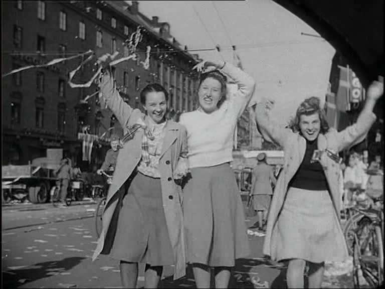 Tre jublande unga kvinnor på Kungsgatan i Stockholm på fredsdagen, 7 maj 1945.