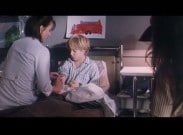 En pojke sitter upp i en sjukhussäng, en sjuksköterska sitter på sängkanten och ger pojken en spruta.
