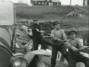 En man och två pojkar halar en dragfärja som det står en bil på.
