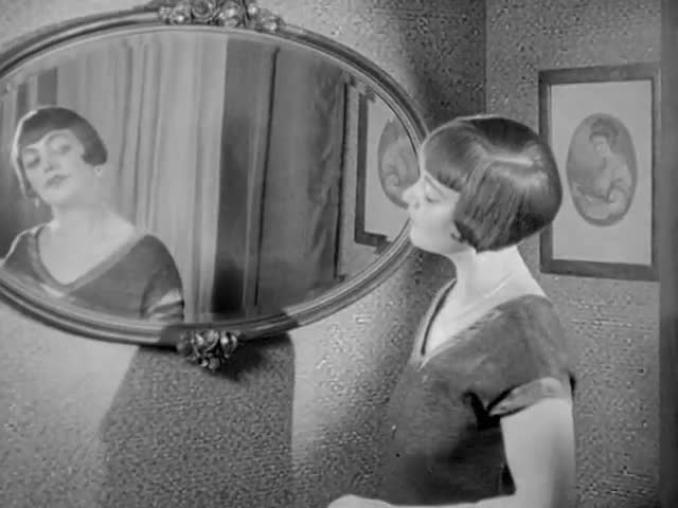 Dam med frisyren shingel med lugg ser sig i spegel.